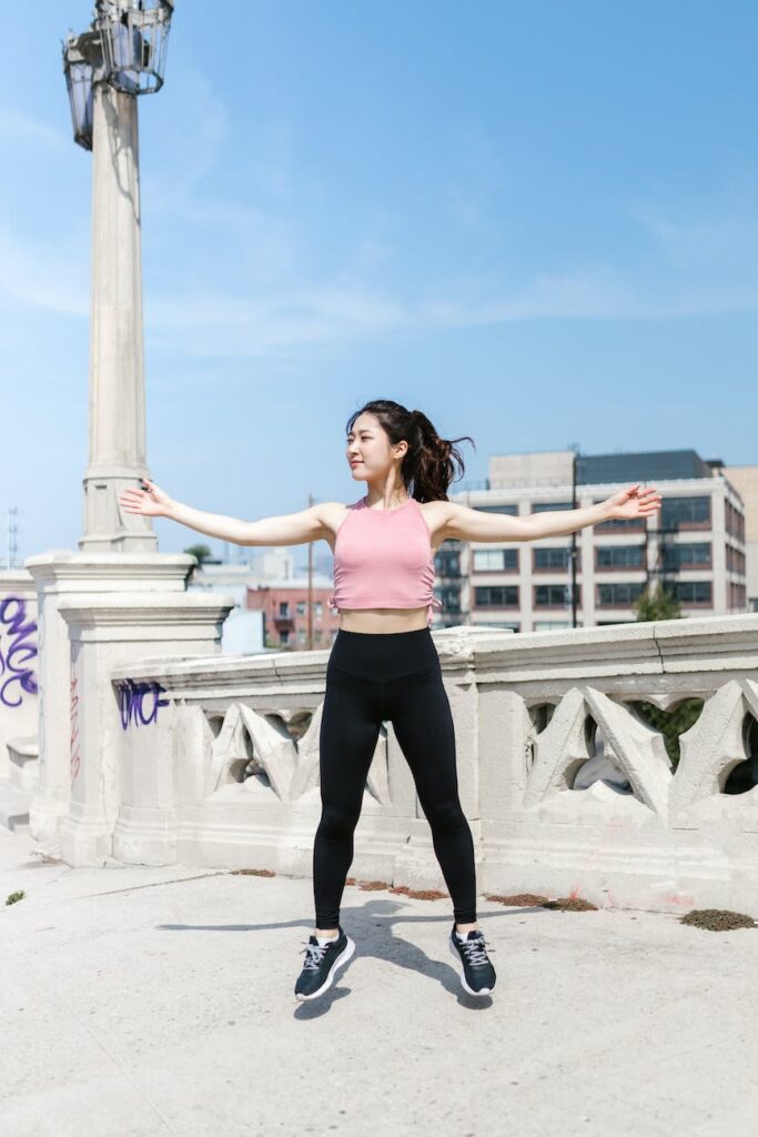 woman wearing pink crop top jumping on concrete floor